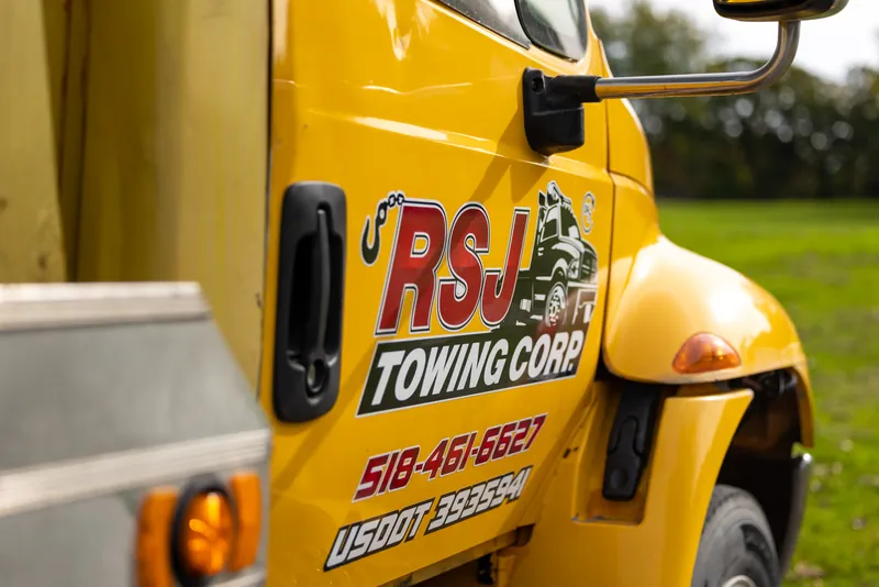Close-up of the RSJ Towing Corp logo on a yellow truck door